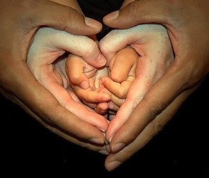 Hands of various skin tones held together forming a heart shape